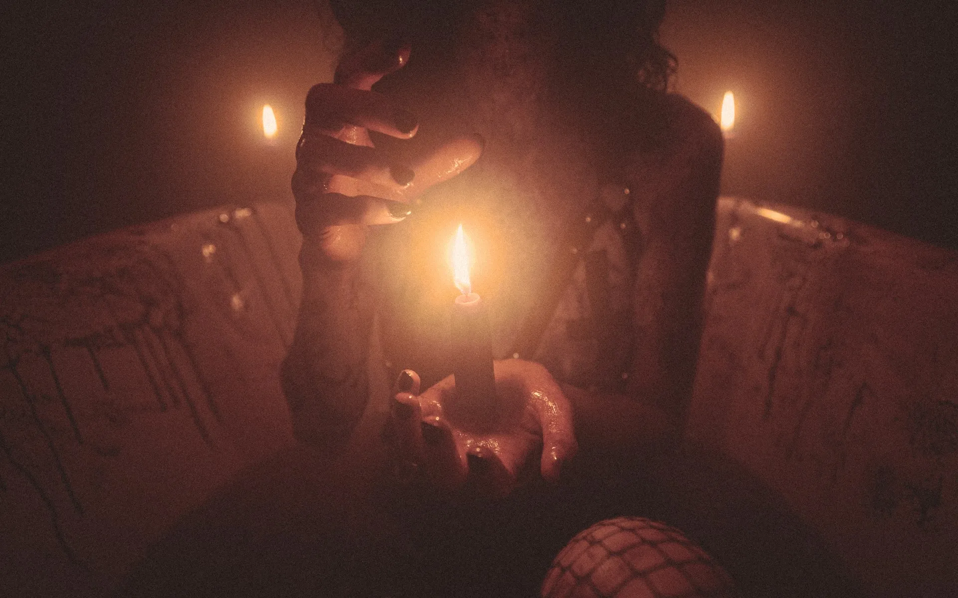 A person holding a lit candle in their hand