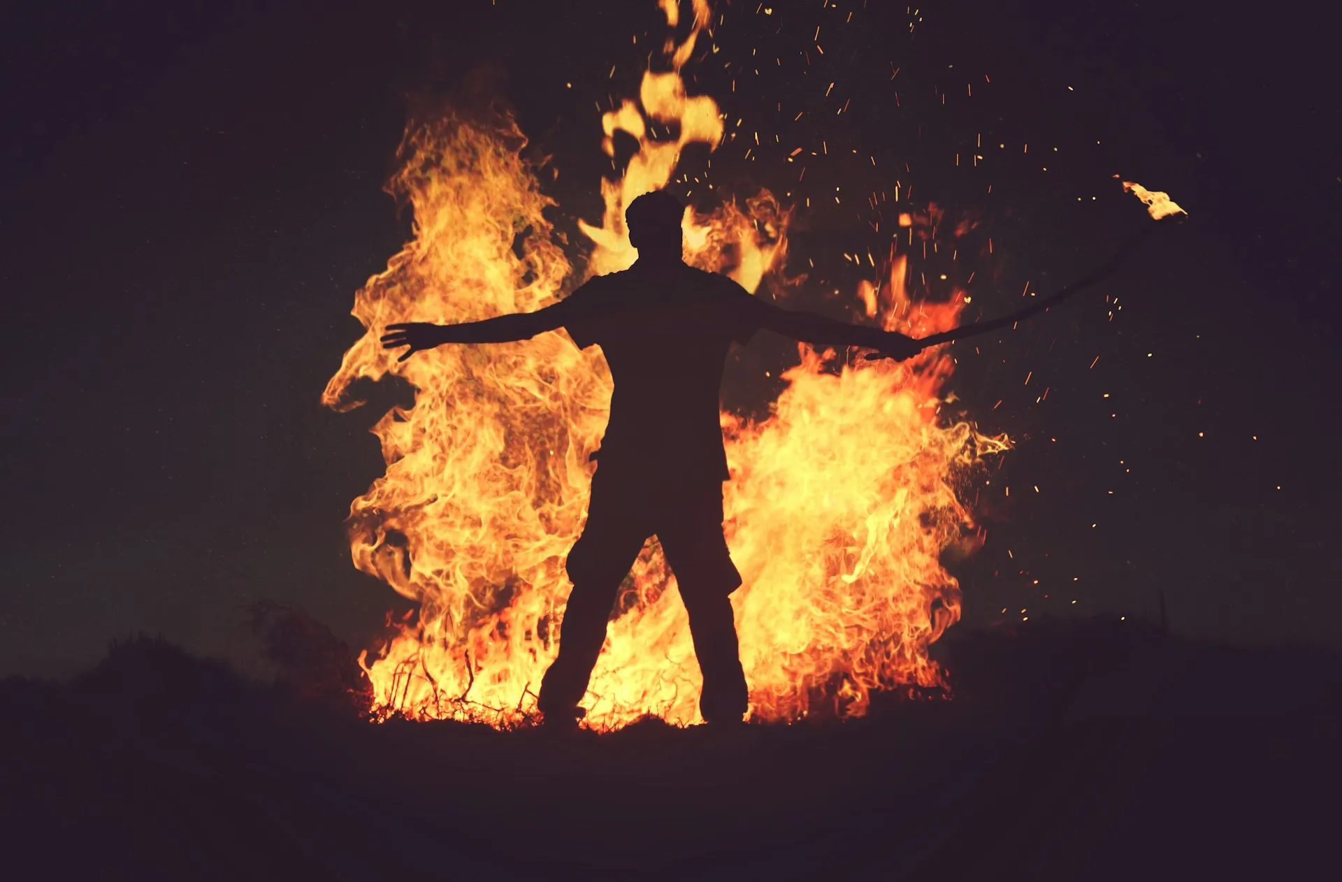 Person standing in front of fire during night time